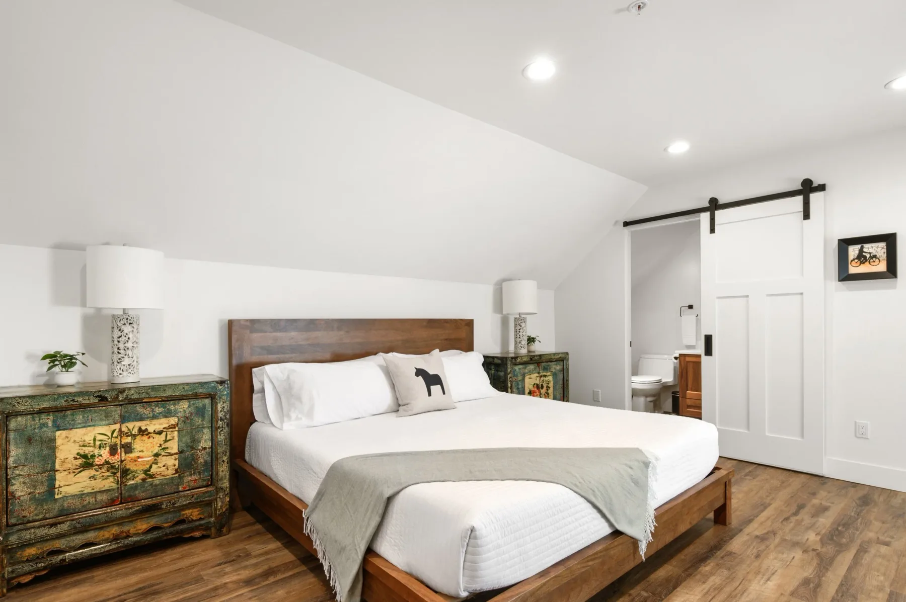 Representative hotel space: A bedroom with a wooden bed, white bedding, and matching bedside cabinets.