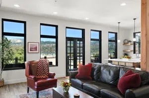 Representative hotel space: A bright living room with seating beside tall windows.