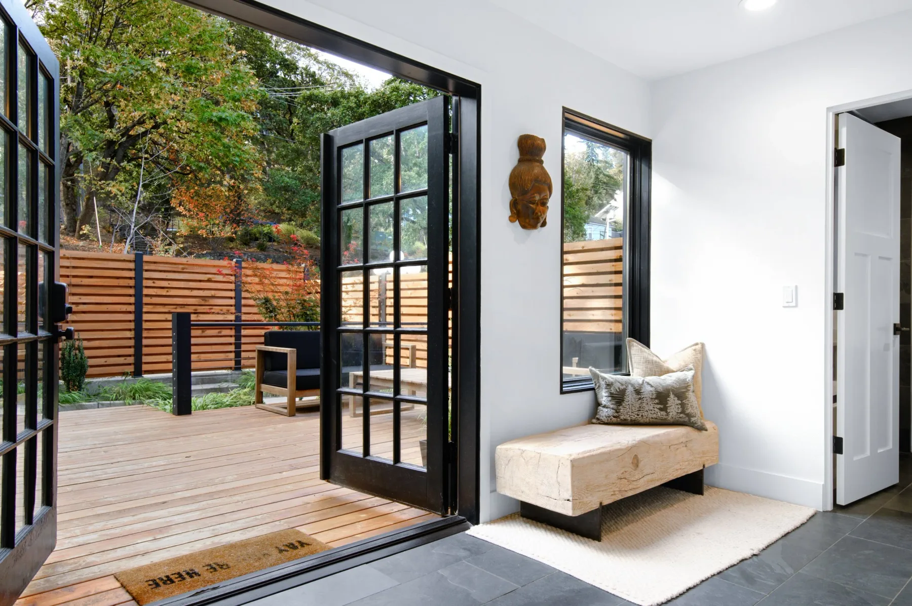 Representative hotel space: A bright interior opens onto a wooden deck through wide glass doors.