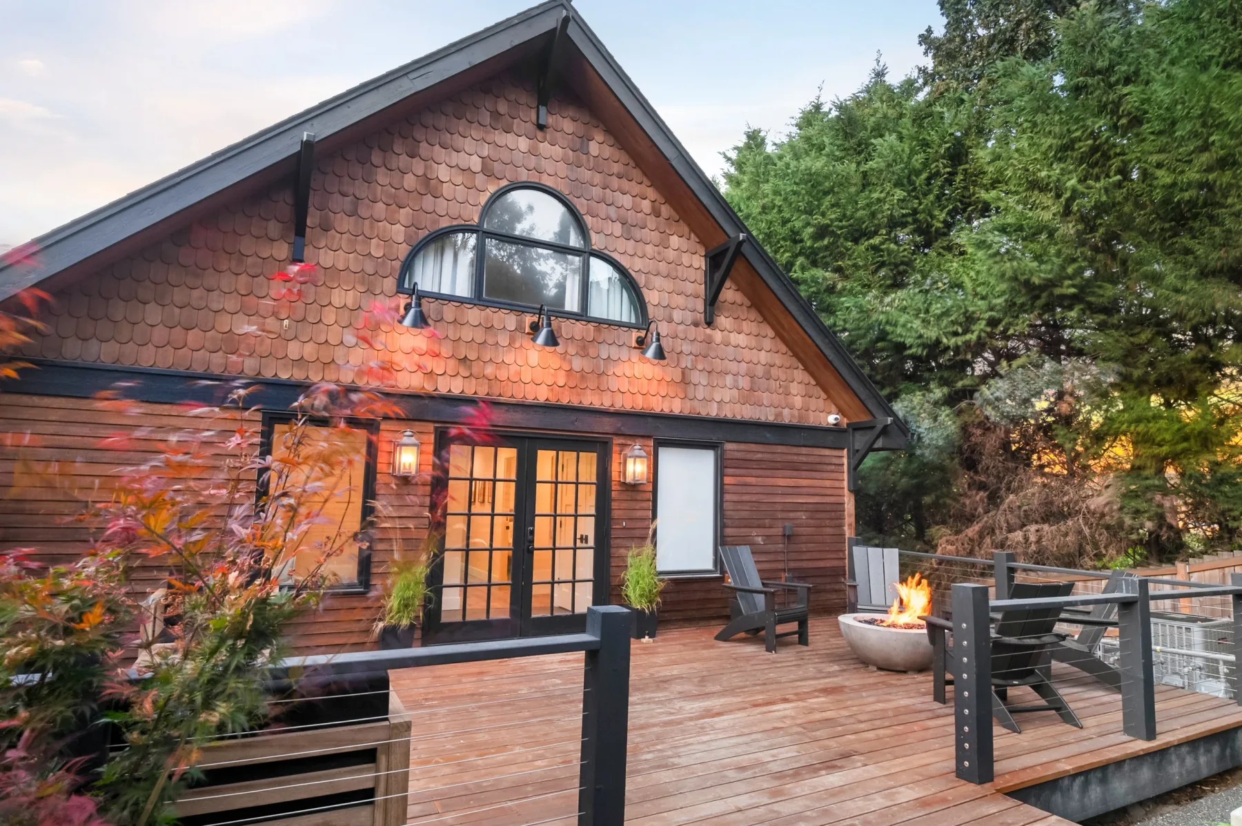 Representative hotel space: A wood-sided cabin opens onto a deck with outdoor seating and a fire pit.