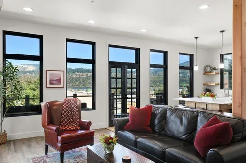 Representative hotel space: A bright living room with dark seating beside tall windows.