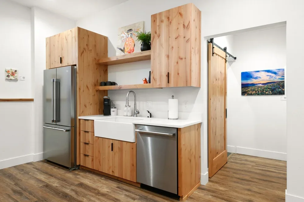 Representative hotel space: A compact kitchen with wood cabinets, a sink, and stainless-steel appliances.