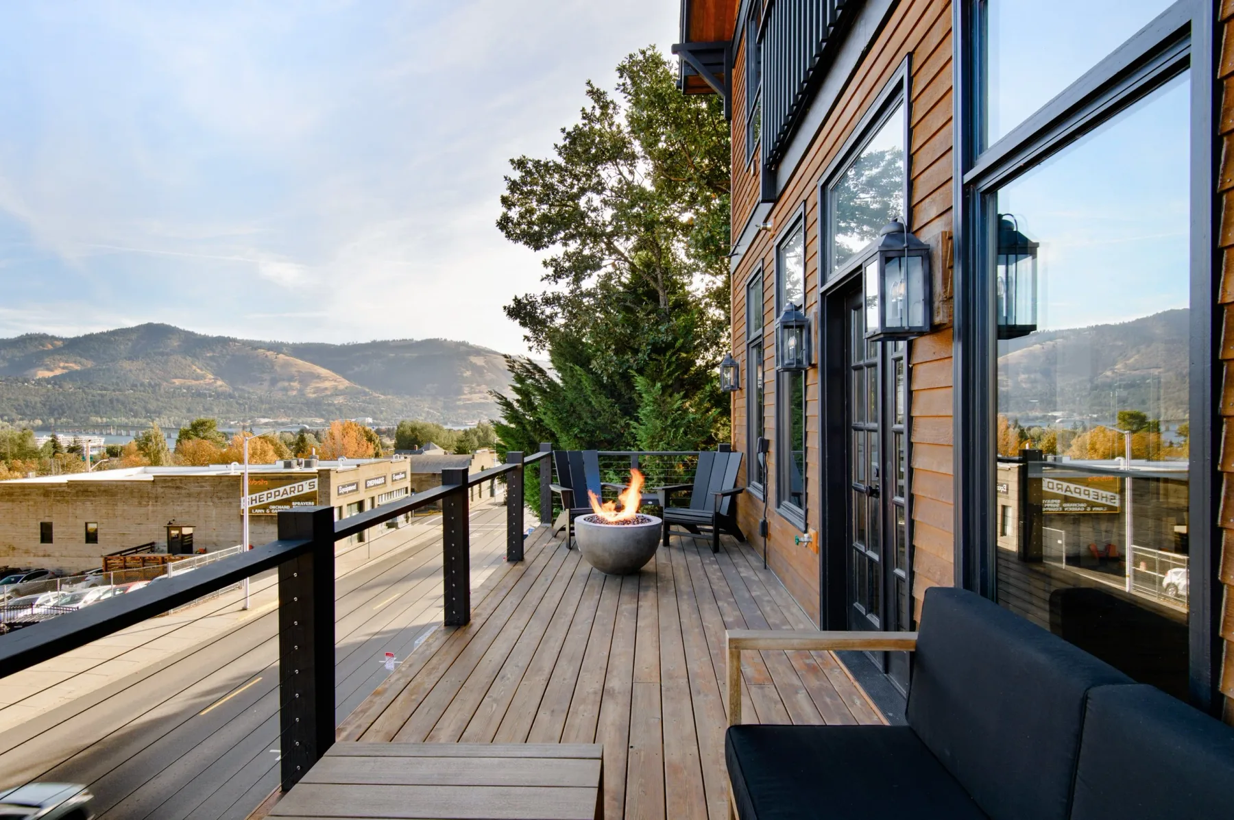 Representative hotel space: A wooden outdoor deck with seating and a fire pit overlooks a mountain landscape.