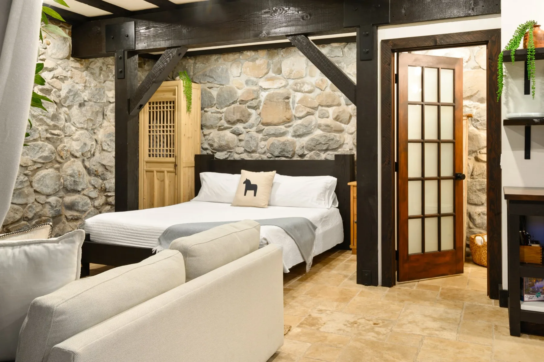 Representative hotel space: A bedroom with a bed, light seating, and exposed stone walls.