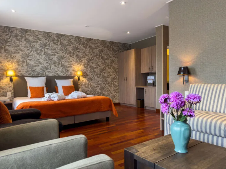 Espacio representativo del hotel: Un dormitorio de hotel con dos camas, papel pintado estampado y una zona de estar.
