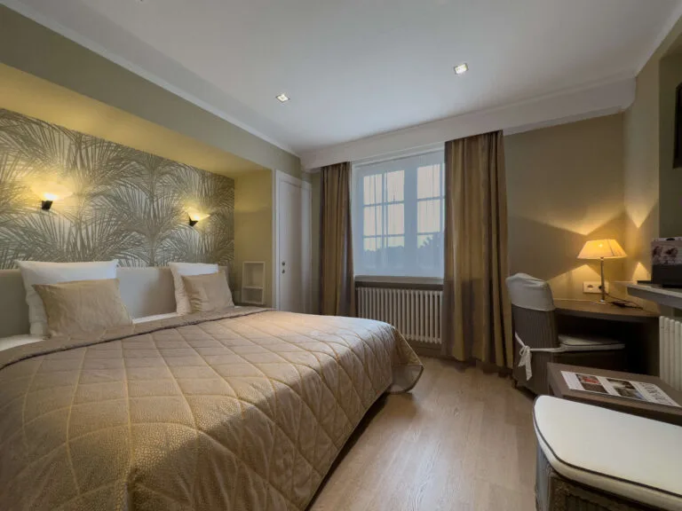 Espacio representativo del hotel: Un dormitorio de hotel con una cama grande, una pared estampada y un escritorio junto a la ventana.
