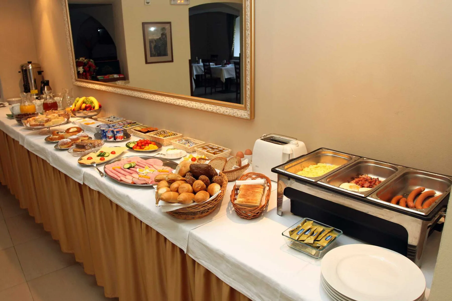 Espacio representativo del hotel: Una mesa de bufé presenta alimentos de desayuno, pasteles y fuentes.