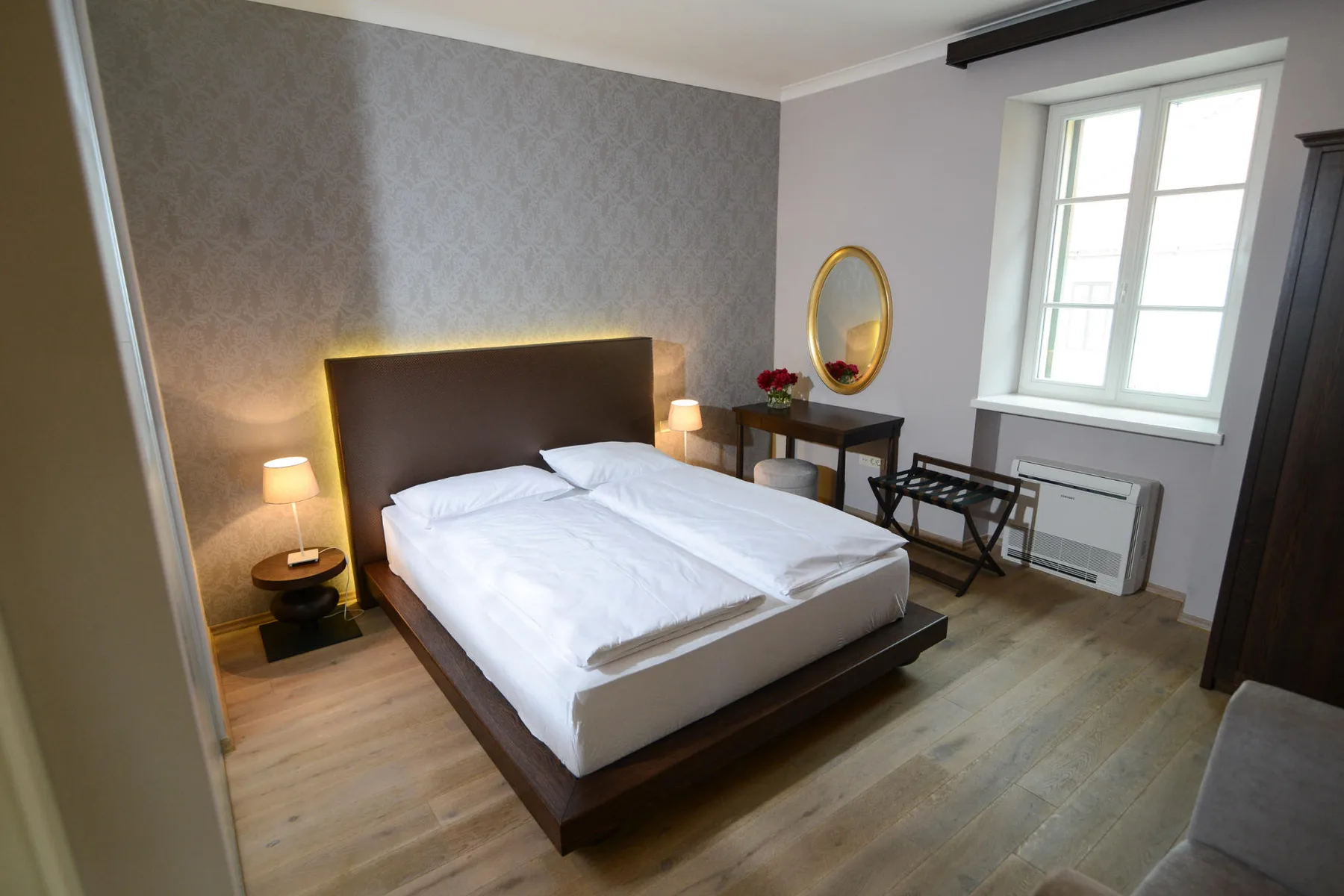 Representative hotel space: A bedroom with a double bed, bedside lamps, and a window.