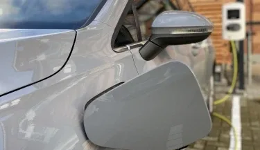 Representative hotel space: Close-up of an electric car charging beside a brick wall.