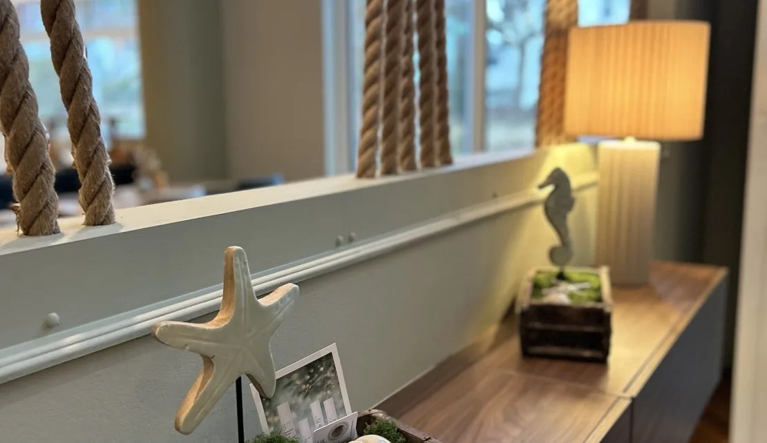Representative hotel space: A wooden console table displays a lamp and decorative items beside a window.