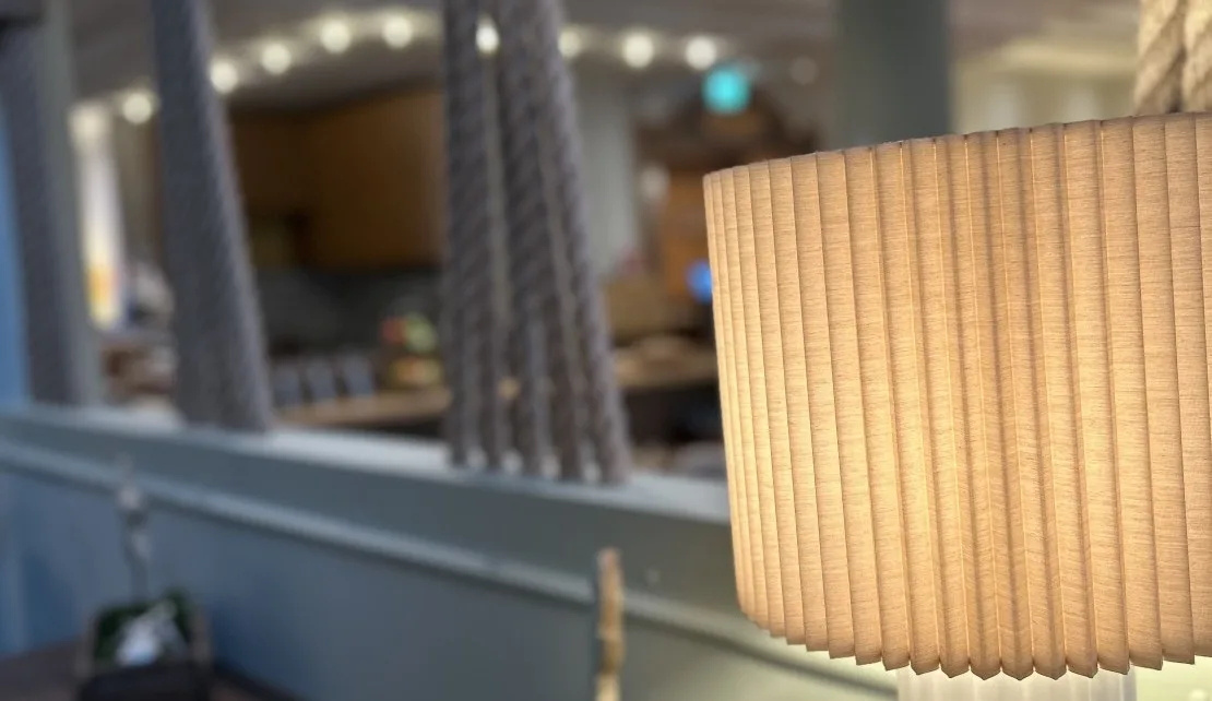 Representative hotel space: A pleated lamp shade fills the foreground of a softly lit interior.