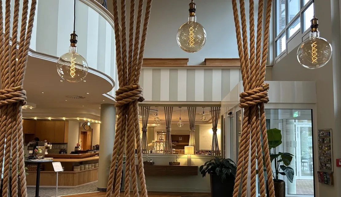 Representative hotel space: A hotel lobby features a reception desk beneath hanging pendant lights.