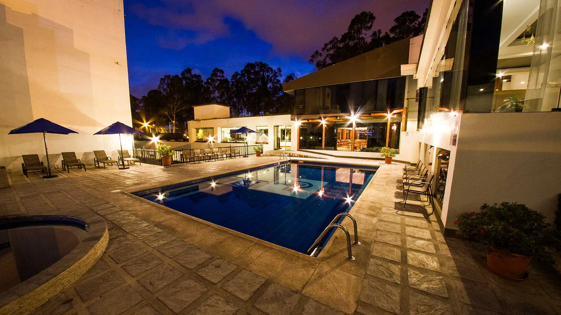 Representative hotel space: An outdoor pool and surrounding patio are illuminated at dusk.