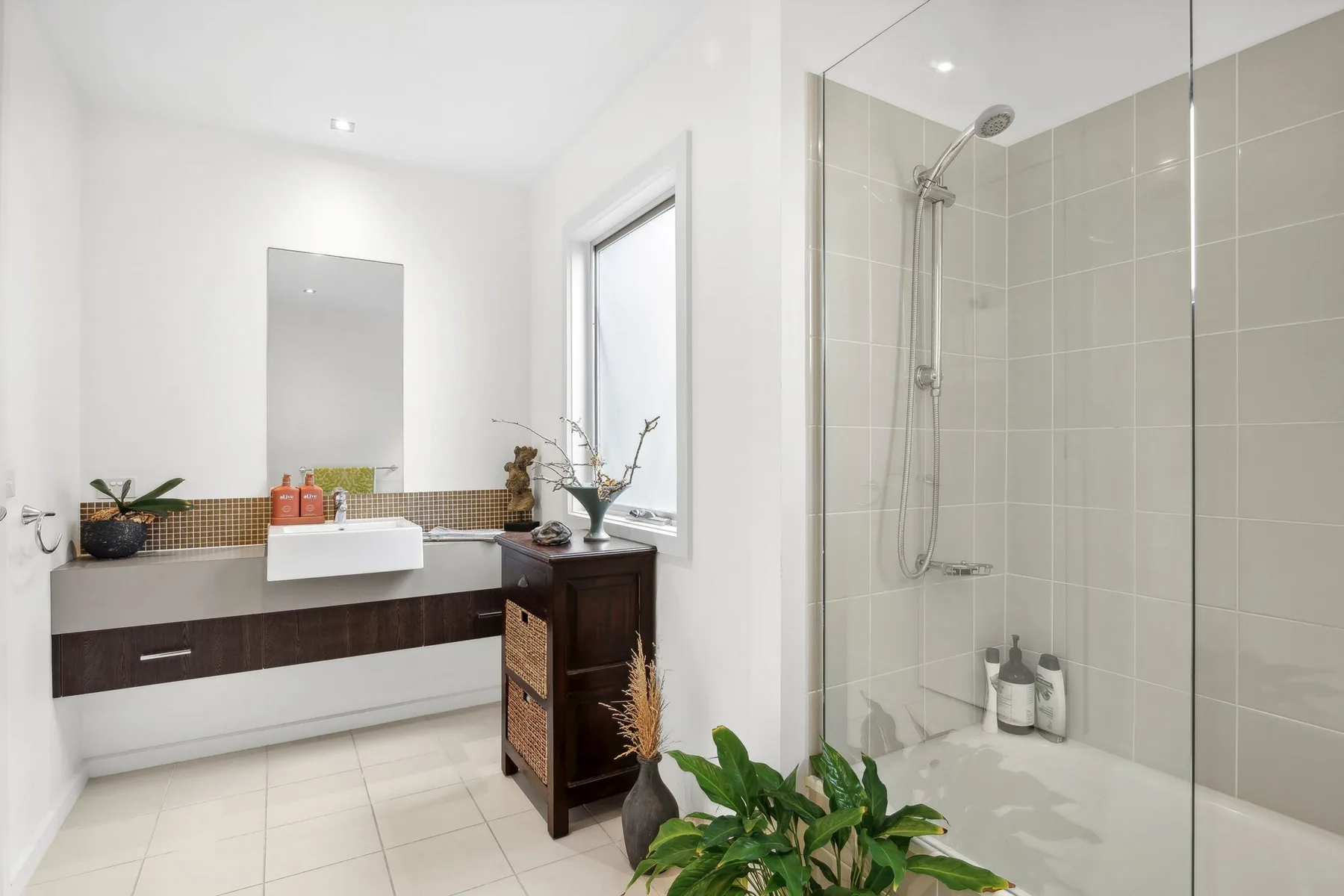 Un baño luminoso con lavabo y ducha de vidrio.