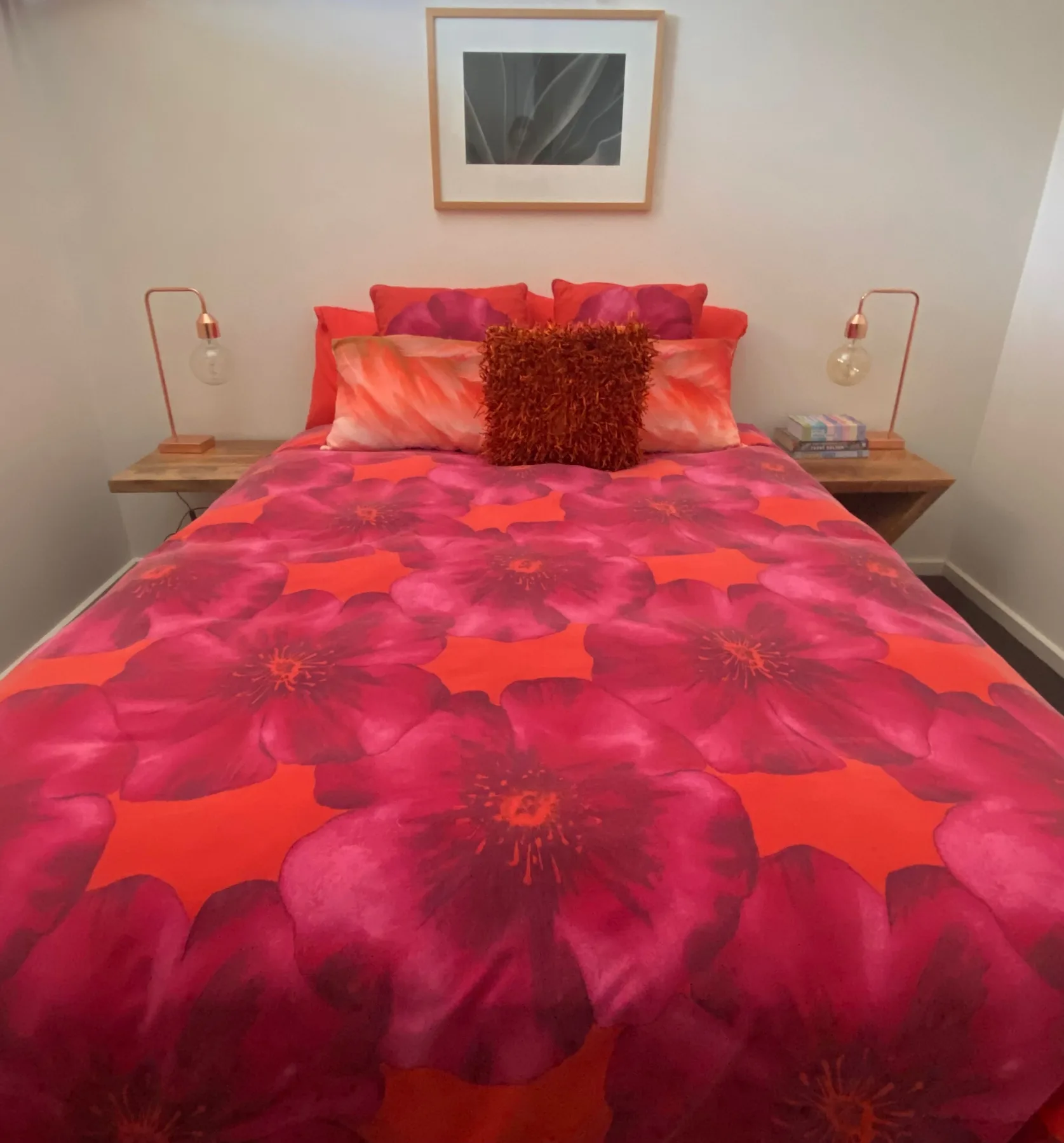 Dormitorio con una cama cubierta de ropa de cama floral en tonos rosa y rojo.