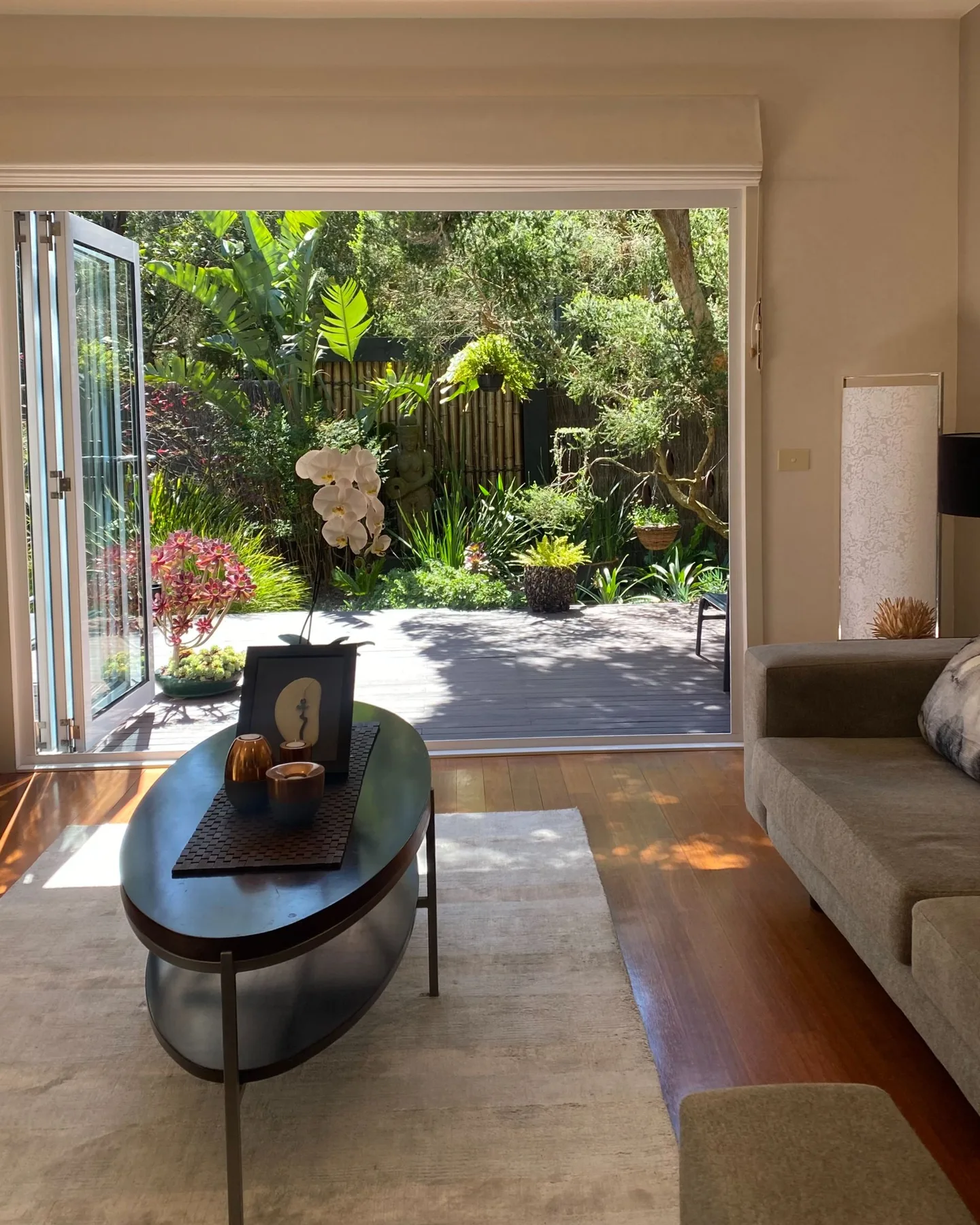 Una sala de estar se abre a un jardín soleado a través de amplias puertas de vidrio.