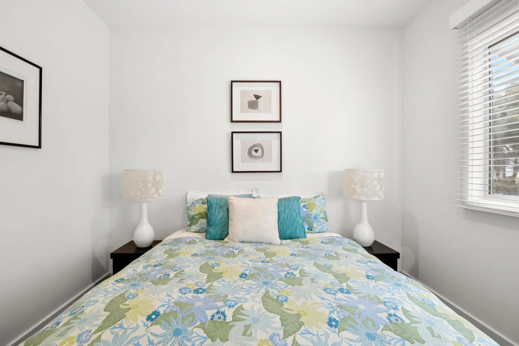 Un dormitorio con una cama vestida con ropa de cama floral azul y verde.