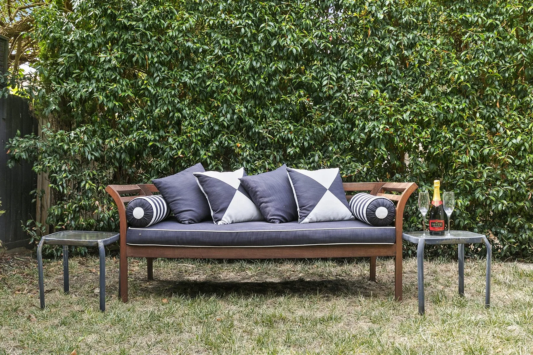 Una zona de asientos al aire libre con un banco acolchado y cojines estampados.