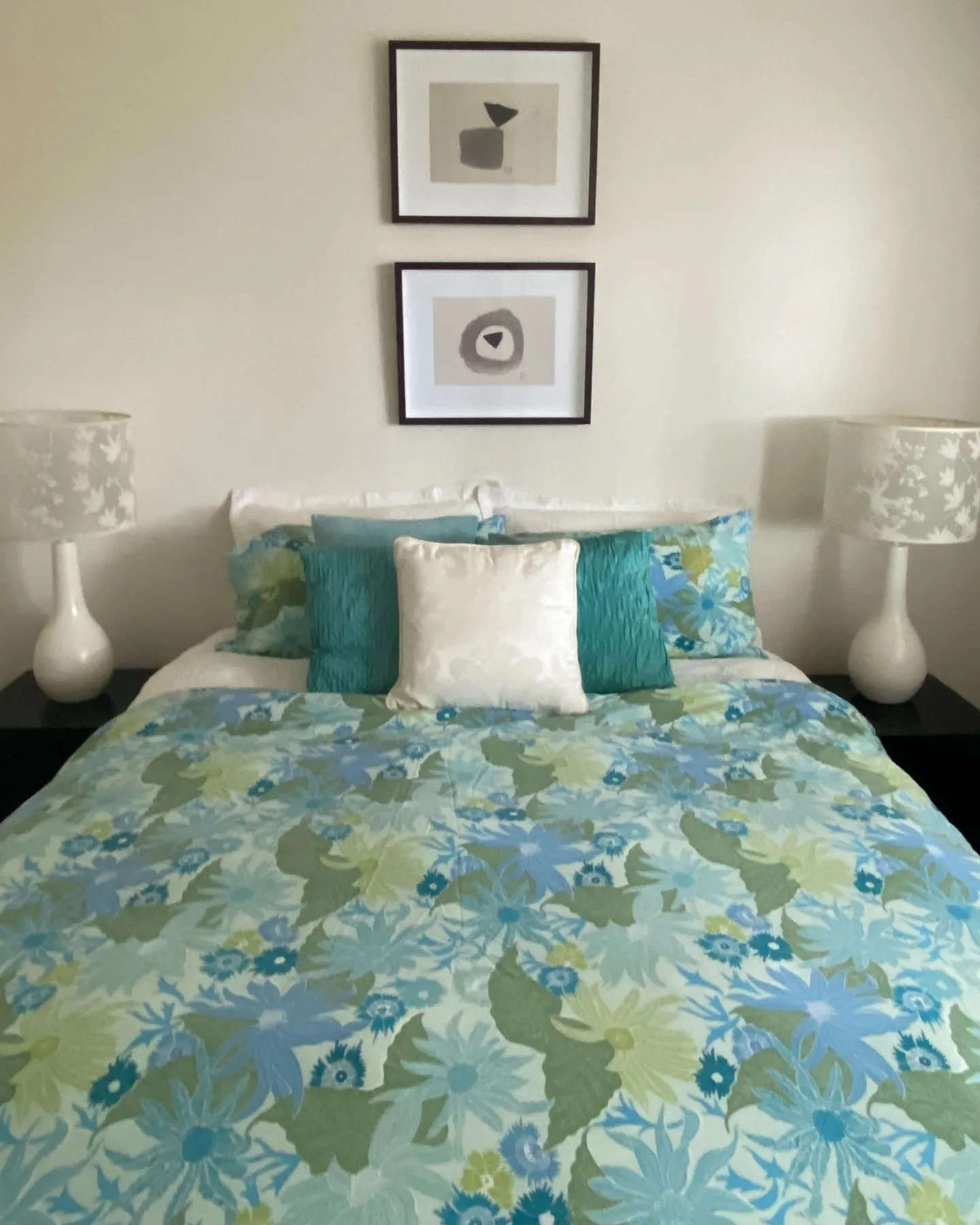Un dormitorio con una cama vestida con ropa de cama floral azul y verde.