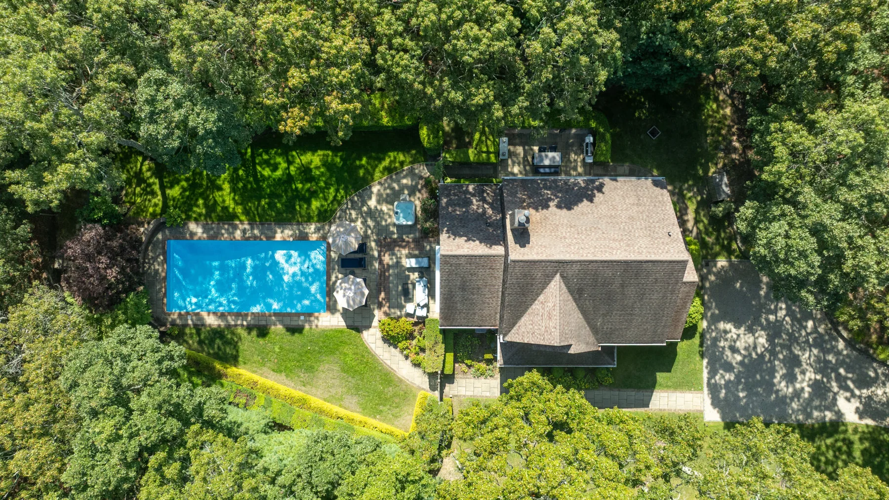 Vista aérea de una casa, una piscina y árboles alrededor.