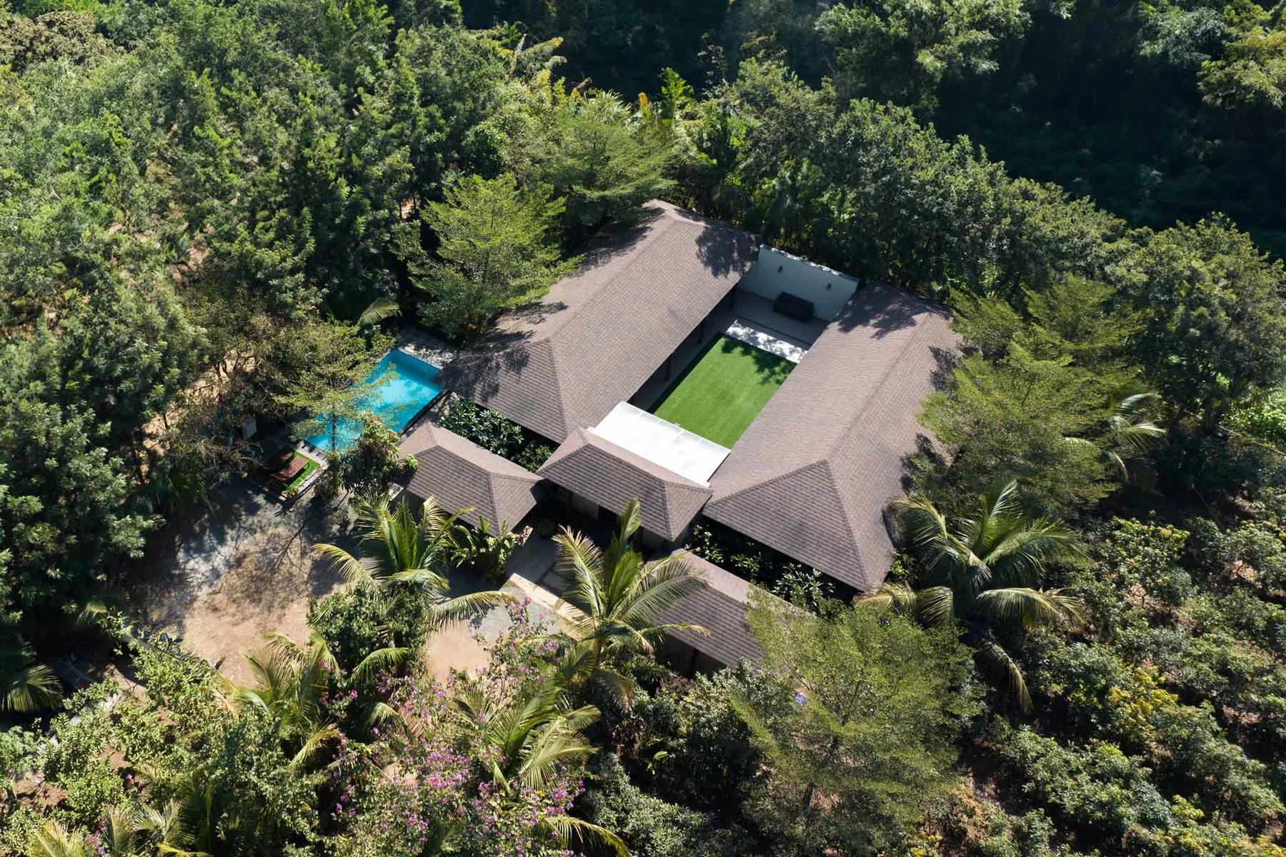 Vista aérea de una casa rodeada de árboles, con una piscina cercana.