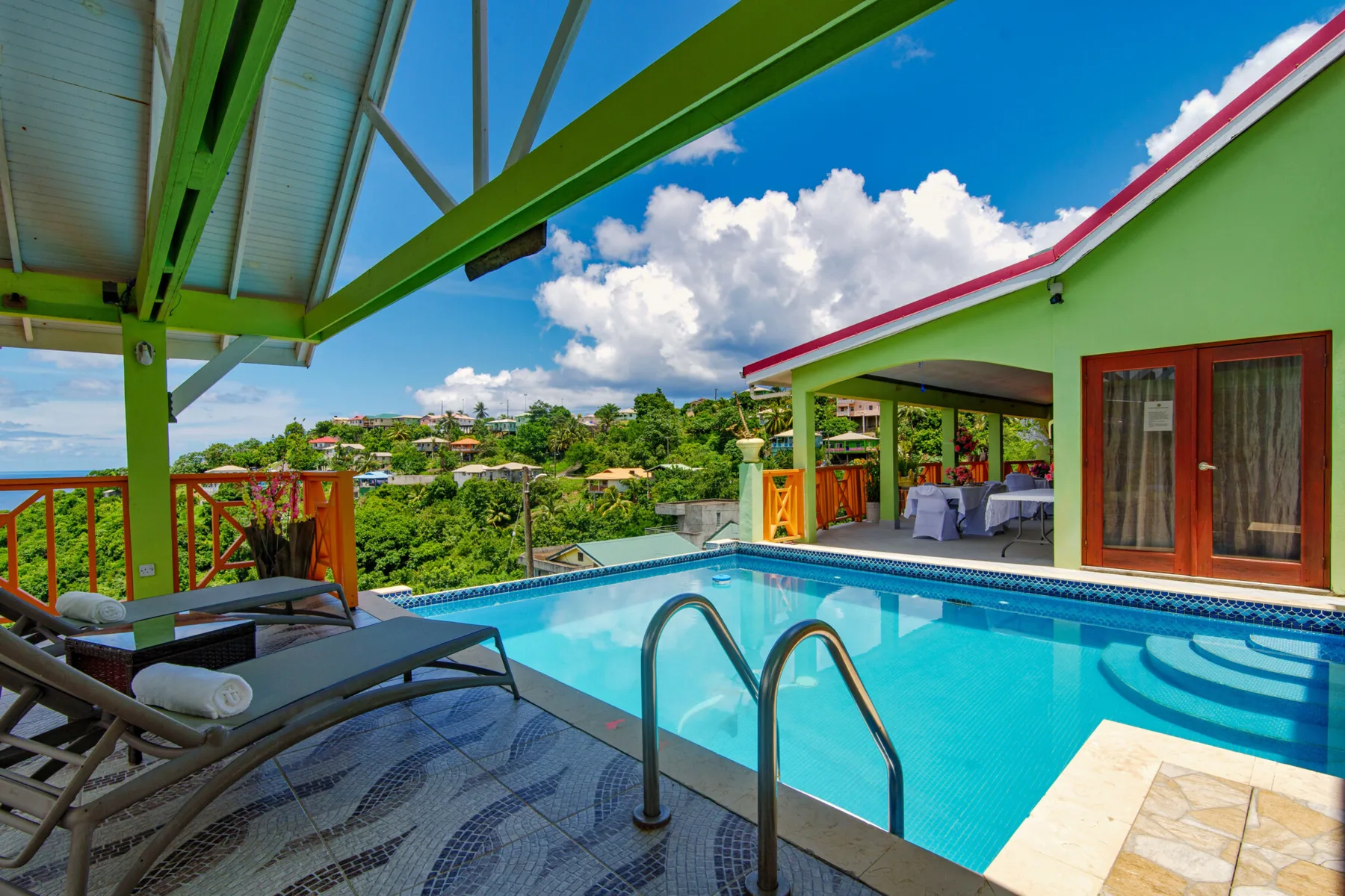 Espacio representativo del hotel: Una piscina al aire libre junto a una zona de estar cubierta y un edificio verde.