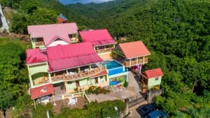 Espacio representativo del hotel: Una vista aérea muestra un conjunto de edificios coloridos rodeado de vegetación densa.