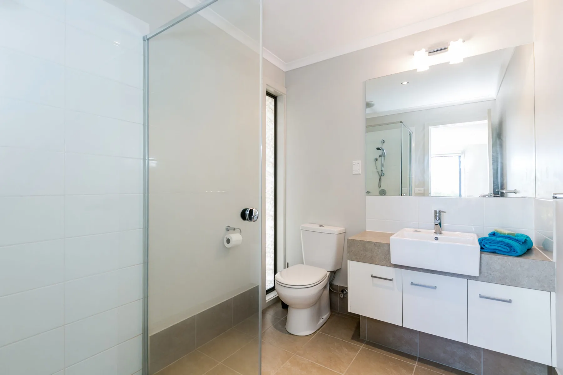 Un baño luminoso con ducha de vidrio, inodoro y tocador.