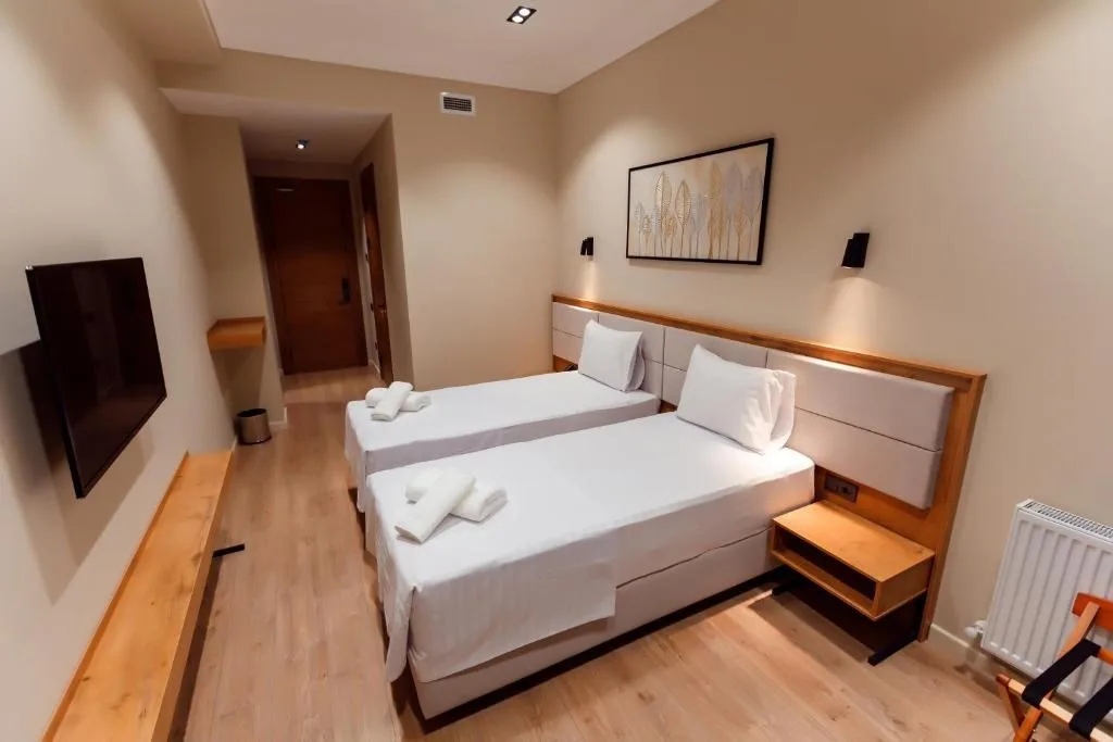 Espacio representativo del hotel: Un dormitorio de hotel con dos camas individuales y un televisor en la pared.