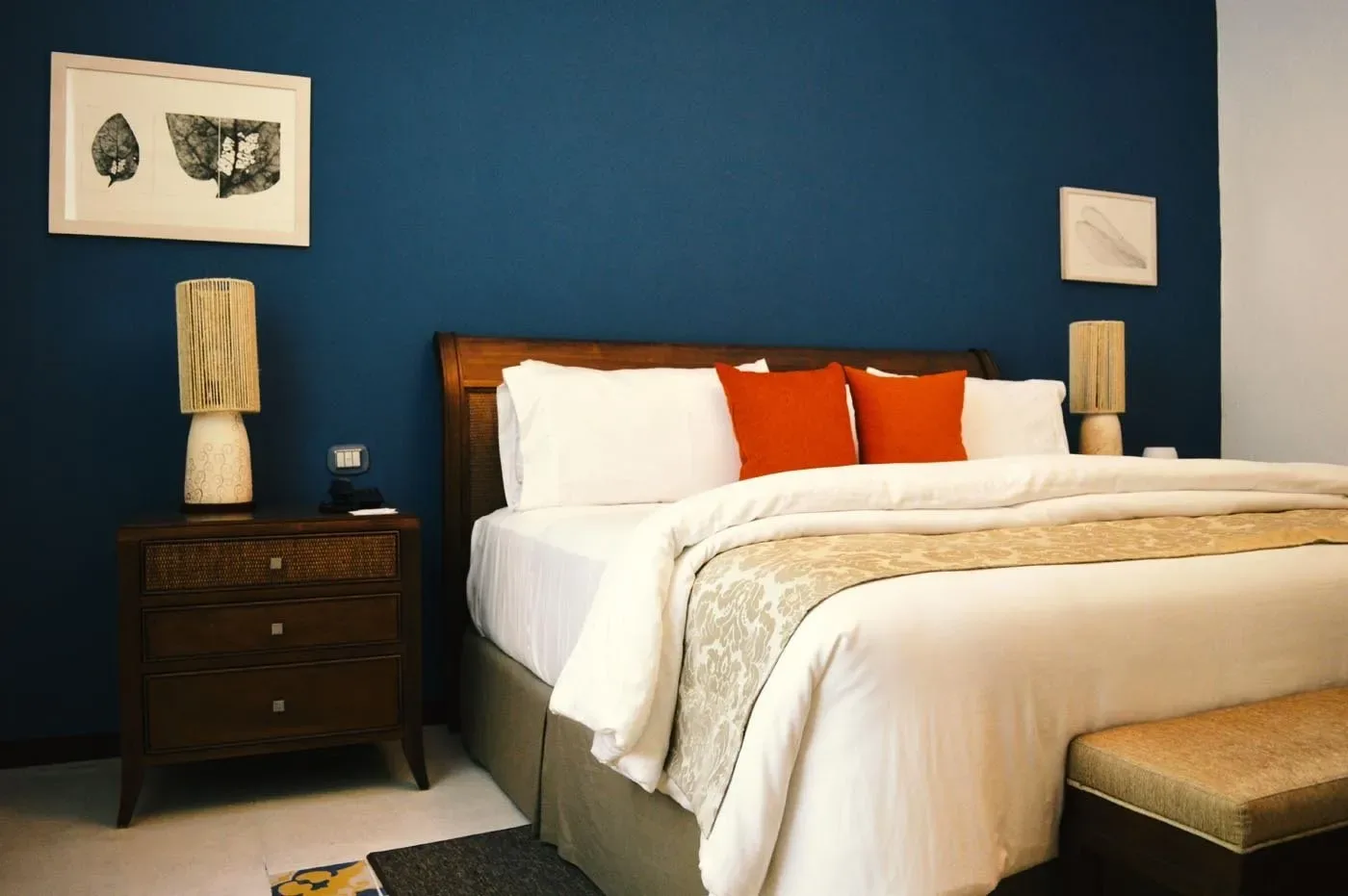Espacio representativo del hotel: Un dormitorio con una cama bien tendida y paredes azul oscuro.