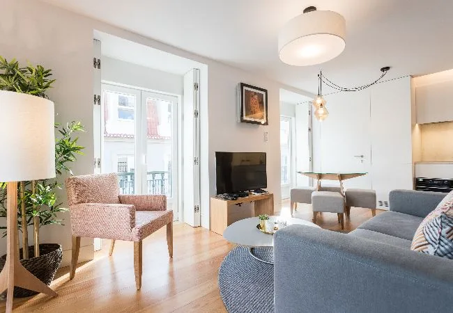Una sala luminosa con asientos, un televisor y un comedor.