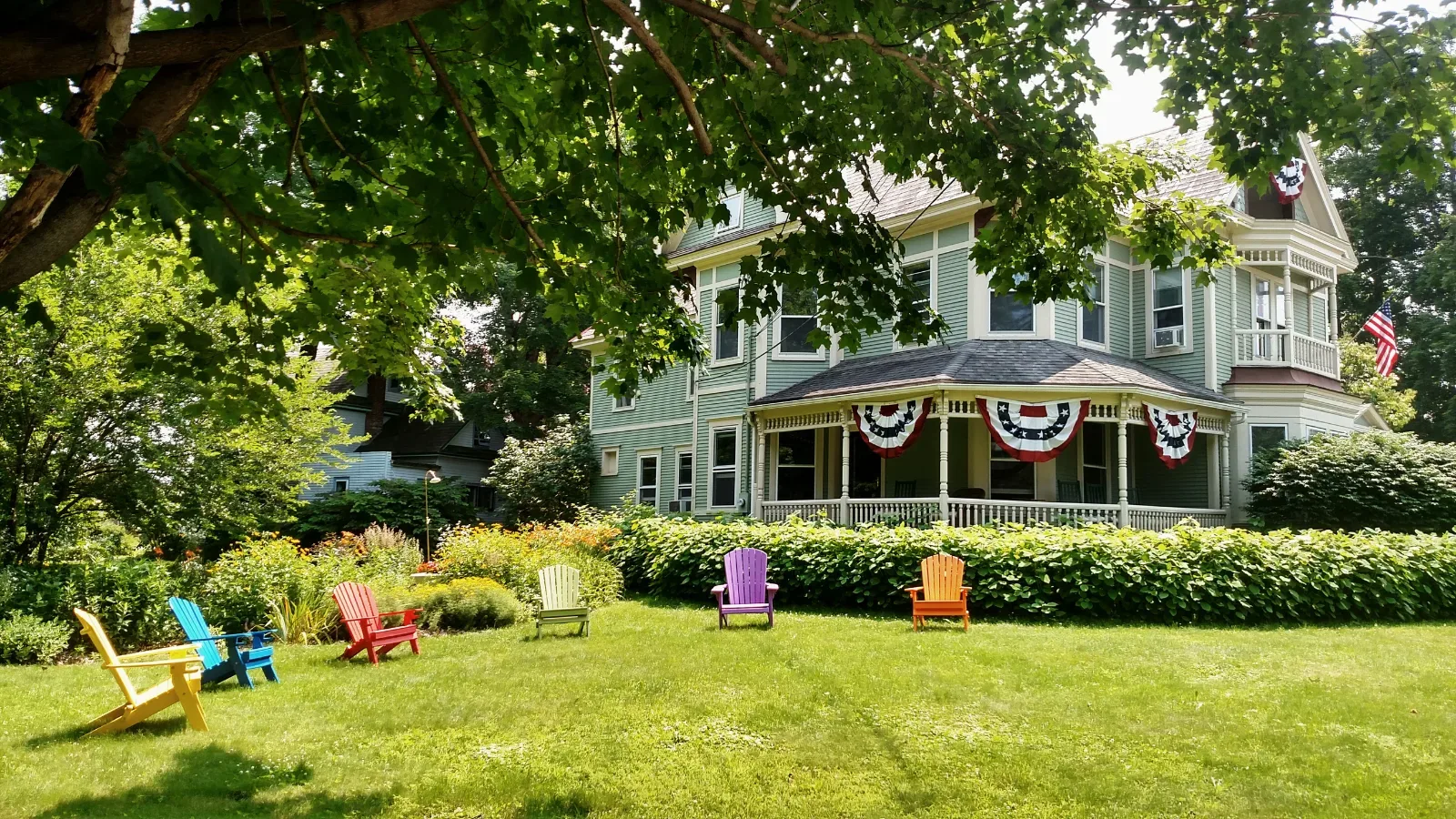 Representative hotel space: A large house stands beyond a green lawn with colorful outdoor seating.