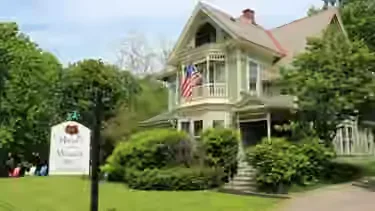Representative hotel space: A large house stands behind a lawn and green shrubs.