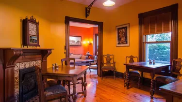 Representative hotel space: An orange-walled sitting room with wooden tables and chairs.