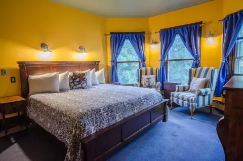 Representative hotel space: A bedroom with a large bed and two striped armchairs by the windows.