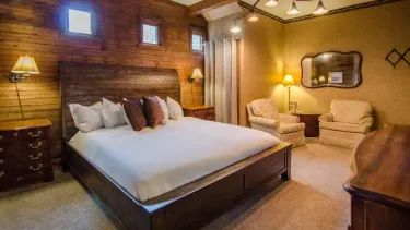 Representative hotel space: A bedroom with a large bed, wooden walls, and seating.