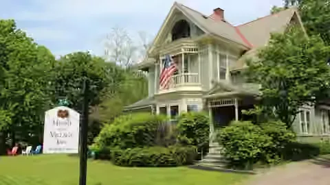 Representative hotel space: A large house stands behind landscaped shrubs and a lawn.