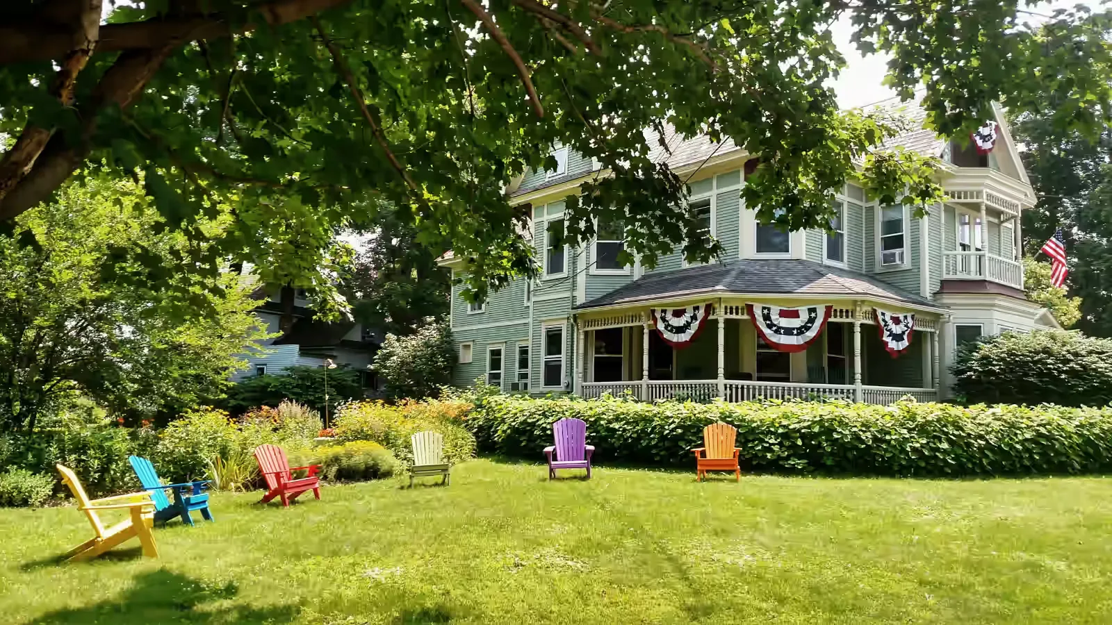 Representative hotel space: A leafy garden lawn with colorful seating in front of a large house.