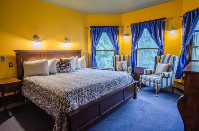 Representative hotel space: A bedroom with a large bed and blue curtains at the windows.