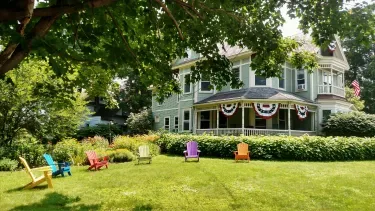 Representative hotel space: A green lawn and garden sit in front of a large house.