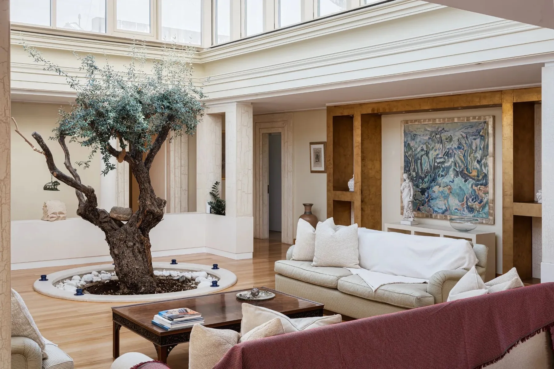 A bright living room with a large tree growing in a circular indoor planter.