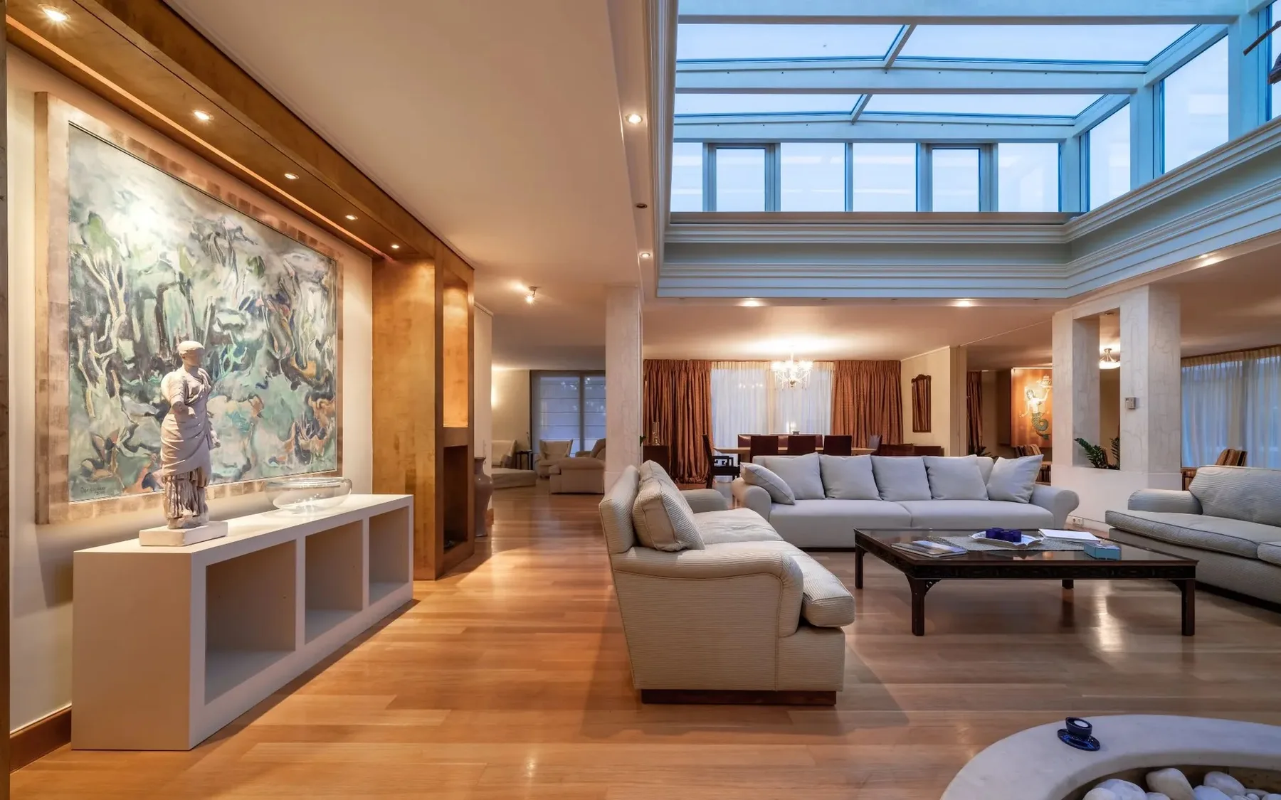 A spacious living room with seating beneath a glass ceiling.