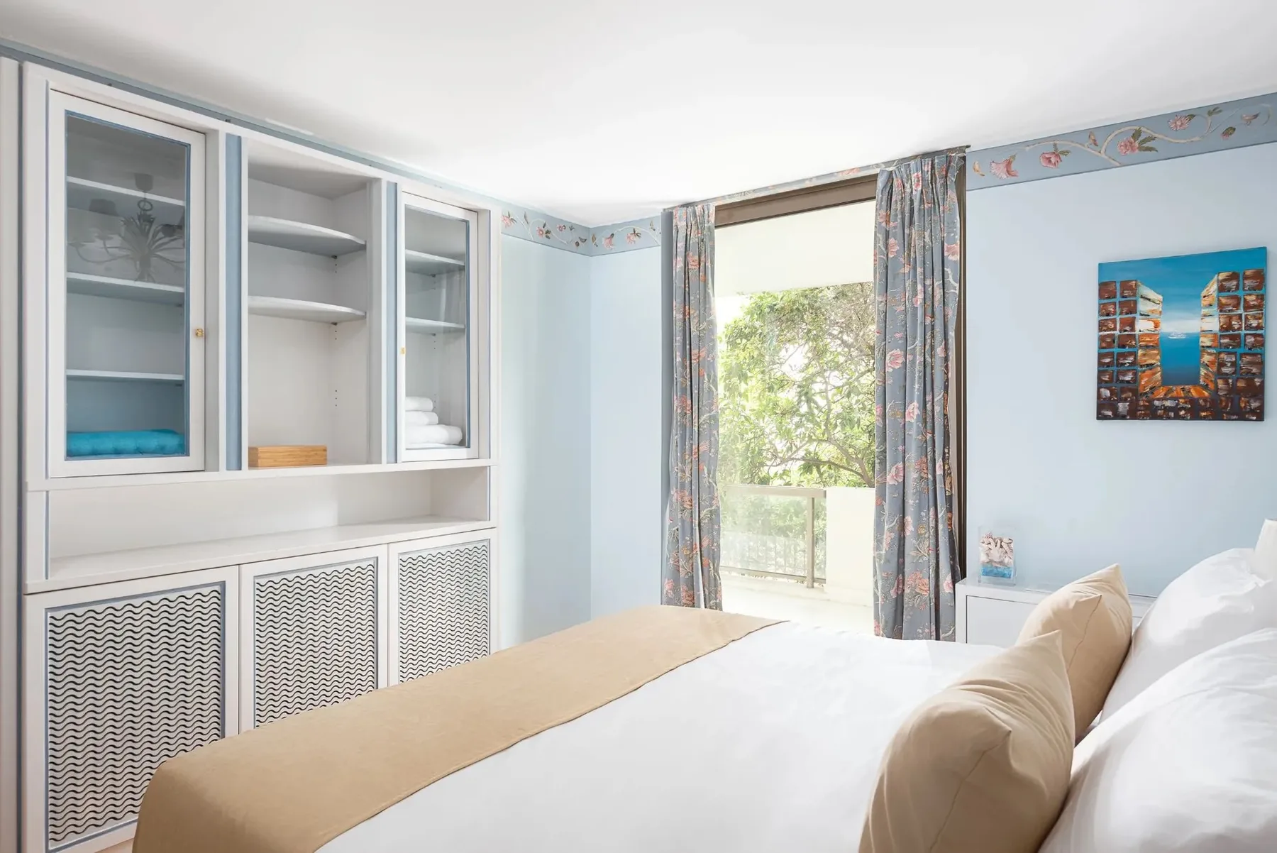 A bright bedroom with built-in cabinets and a curtained window.