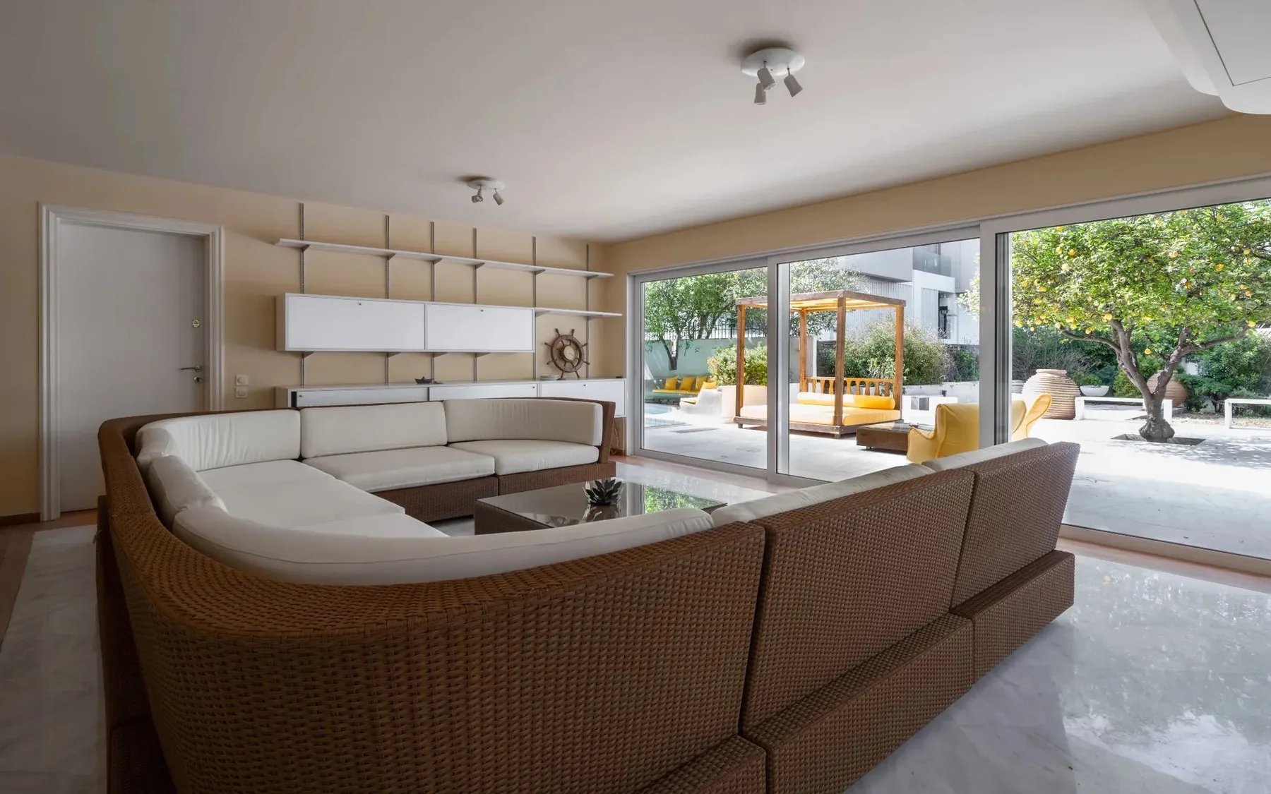 A spacious living room with sectional seating and large windows opening onto a patio.