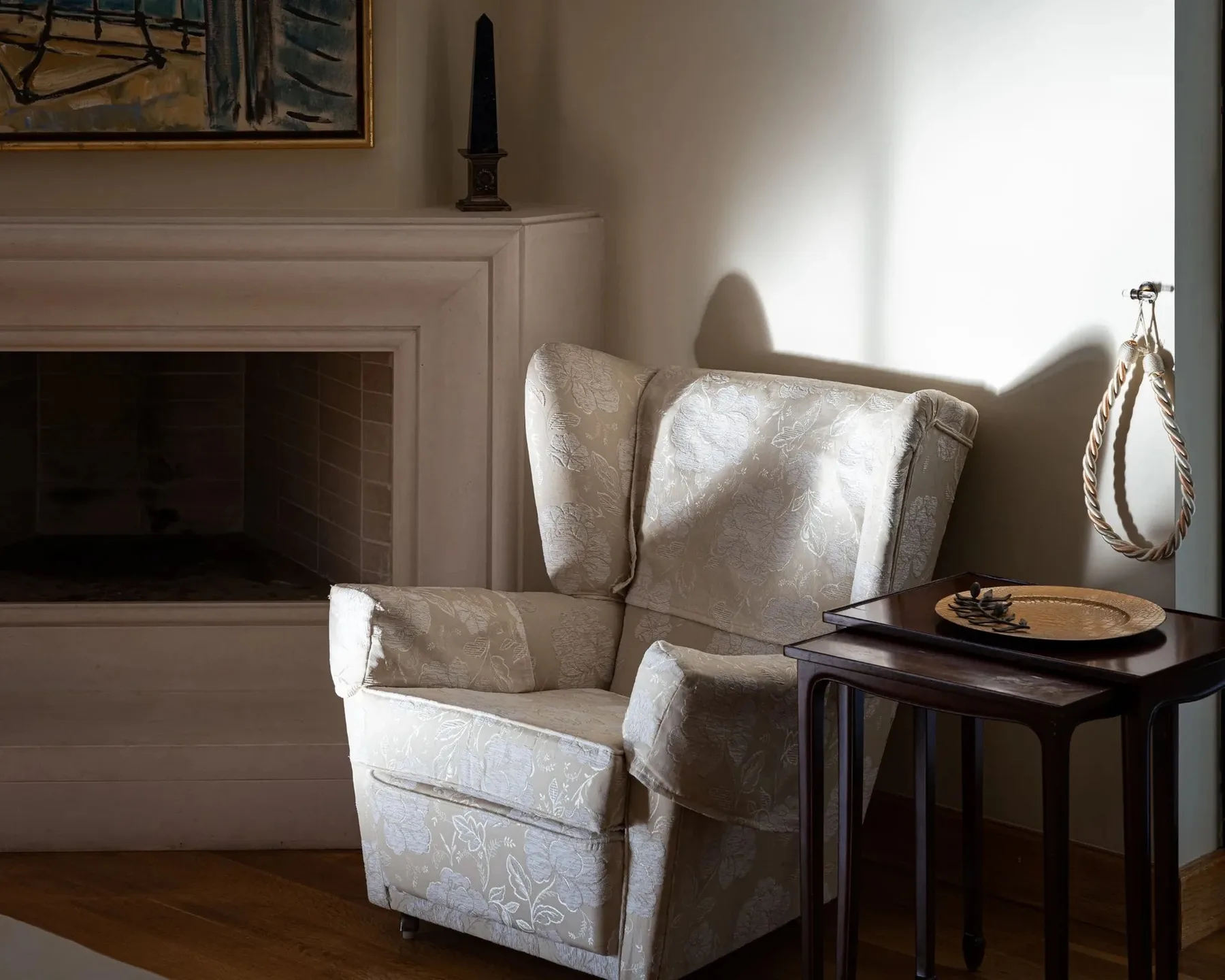 A sitting area with an upholstered armchair beside a fireplace and small table.