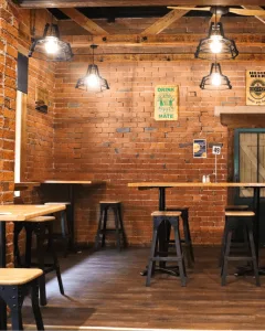 Espacio representativo del hotel: Un comedor con paredes de ladrillo, mesas de madera y taburetes.
