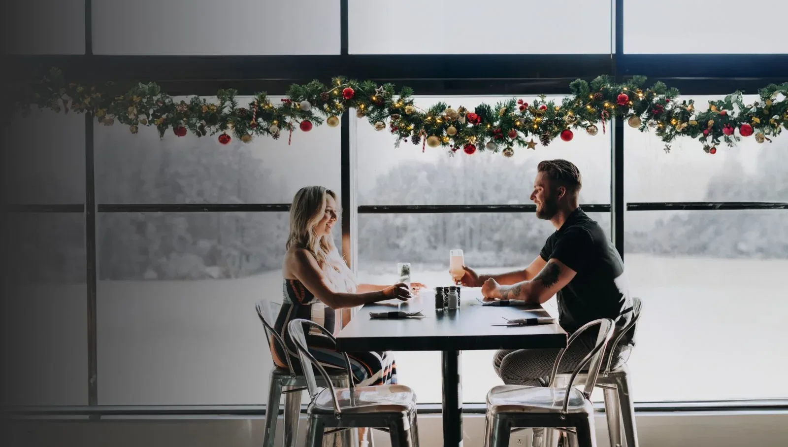 Espacio representativo del hotel: Una pareja se sienta frente a frente en una mesa junto a grandes ventanas.