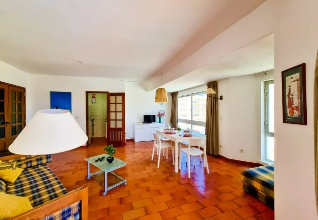 Una luminosa sala de estar y comedor con una mesa junto a grandes ventanas.