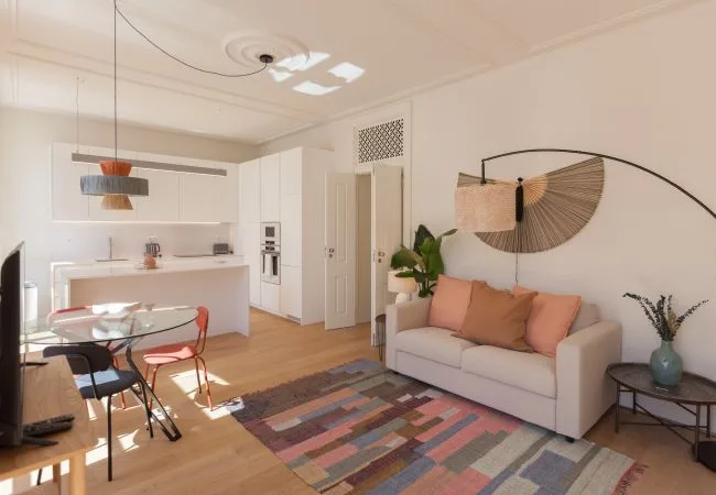 Una luminosa sala de estar y comedor cuenta con un sofá, una mesa y una alfombra colorida.