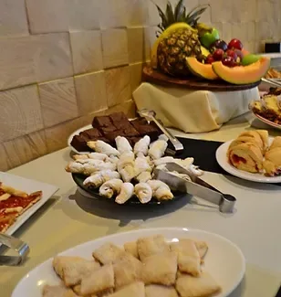Espacio representativo del hotel: Una mesa de bufé muestra pasteles, fruta cortada y otros alimentos.